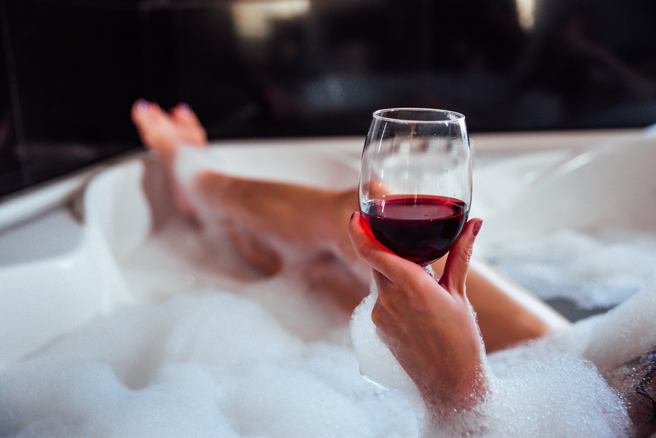 Woman holds wine in a bathtub